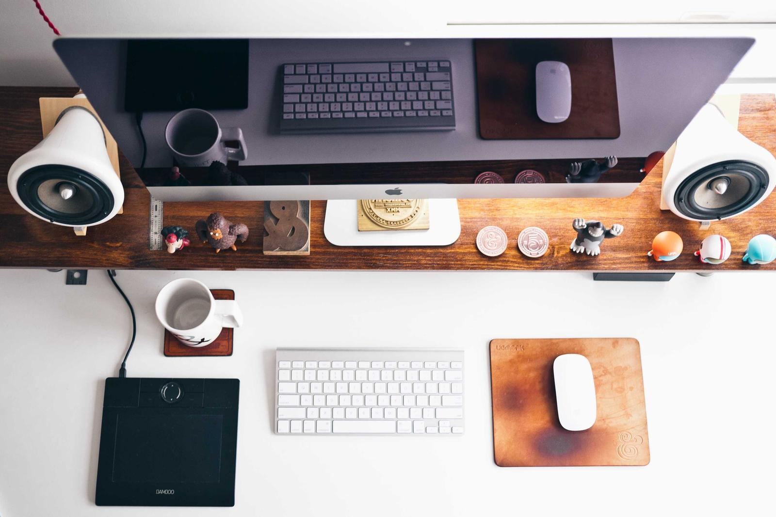 A workspace with two monitors, speakers and a keyboard