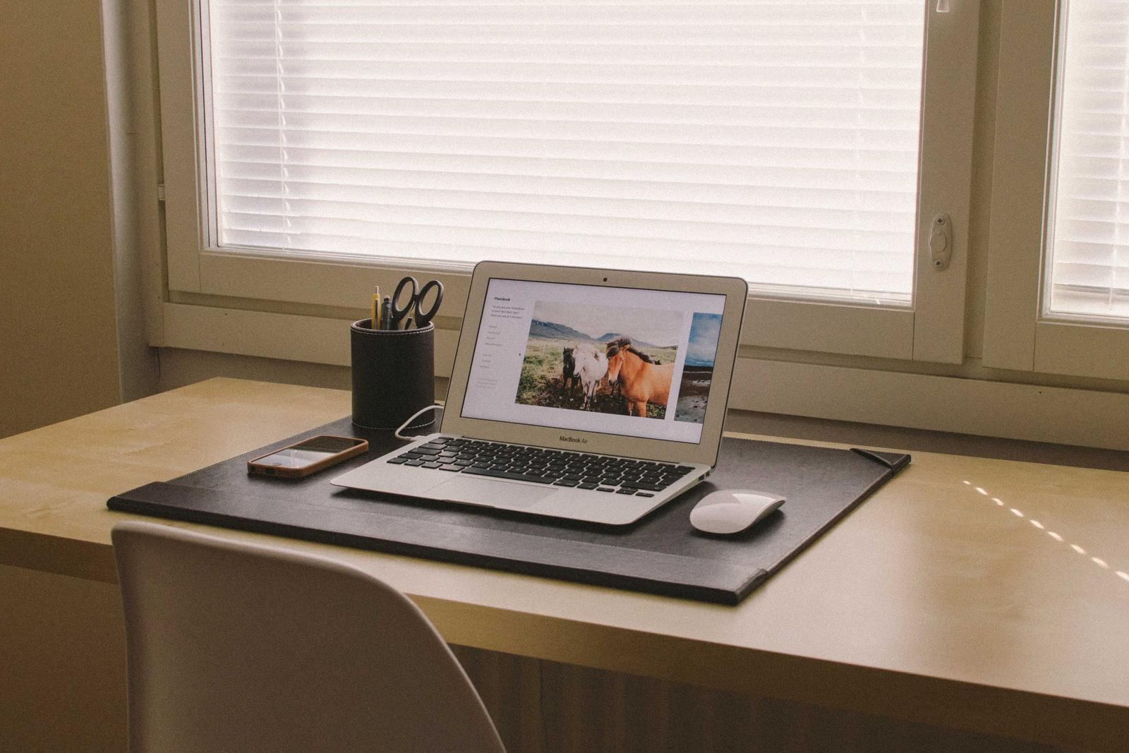 A laptop on a desk by a window in a quiet office